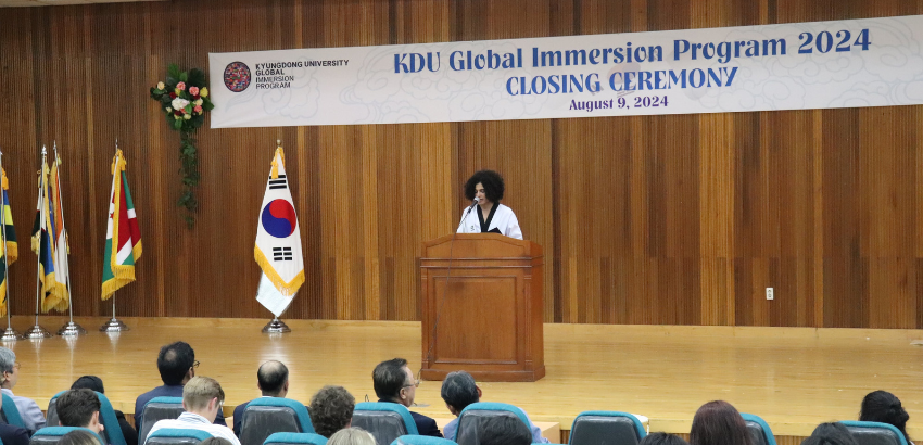 Visão de um palco com o estudante Iago ao centro, falando ao microfone